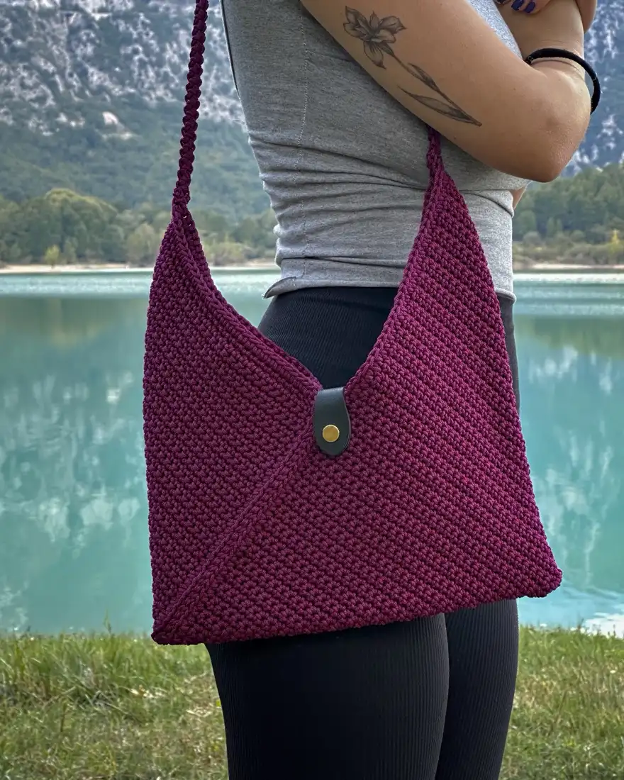 Borsa a tracolla bordeaux indossata in riva a un lago di montagna
